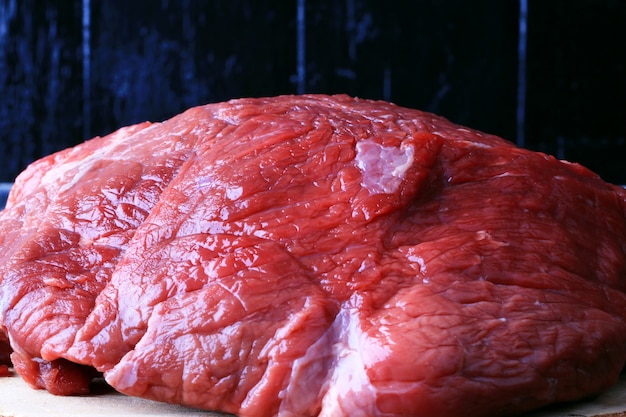 Carne de res cruda en una vieja mesa de madera oscura estilo rústico