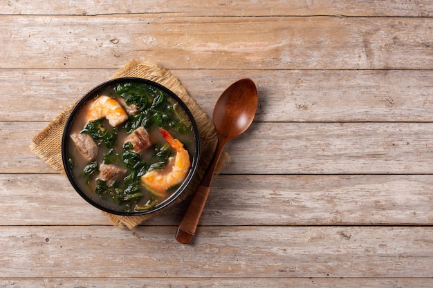 Foto carne de res, estofado de okra y sopa de espinacas en un recipiente sobre la mesa de madera