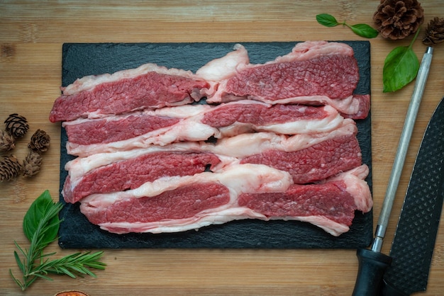 Carne de res fresca en rodajas sobre un plato negro Carne de res en rodajas sobre fondo de madera