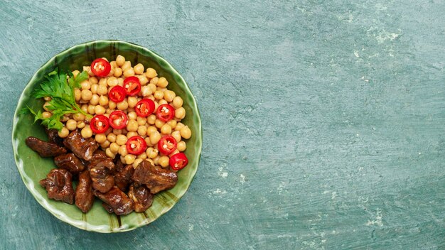 Foto carne de res frita en una sartén con garbanzos y chiles vista superior de primer plano