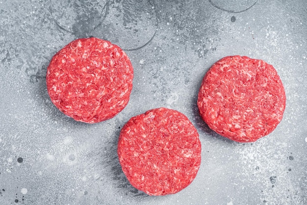 Foto carne de res molida cruda chuletas de filete de hamburguesa. fondo gris. vista superior.