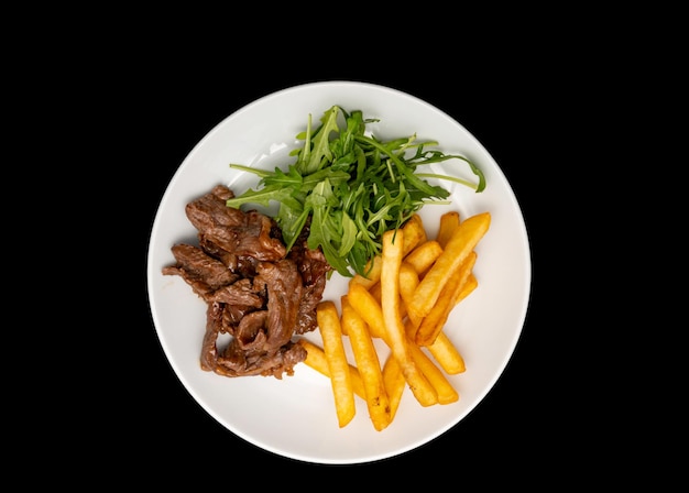 Carne de res salteada servida con papas fritas y hojas de rúcula en un plato blanco Vista superior o puesta plana