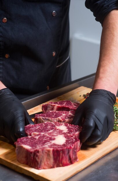 Carne de res en trozos en el tablero y manos humanas.