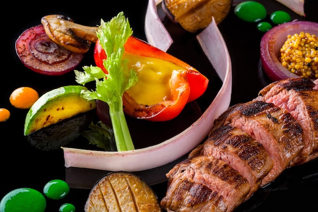 Carne en rodajas con hierbas frescas, verduras y especias sobre fondo negro vista superior