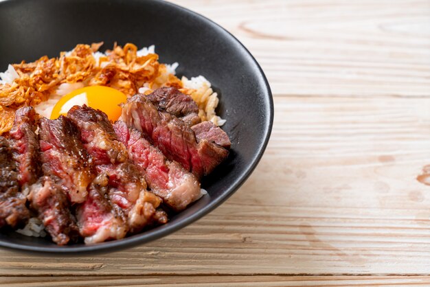 carne en rodajas en un tazón de arroz cubierto con huevo