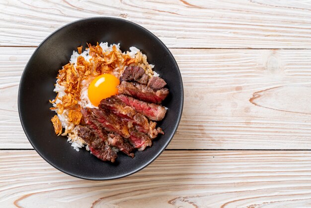 carne en rodajas en un tazón de arroz cubierto con huevo