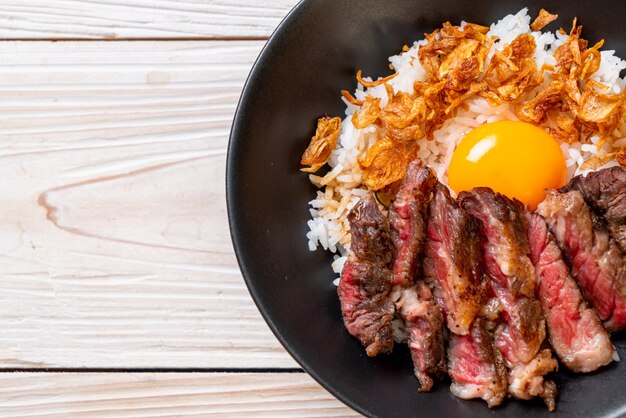 carne en rodajas en un tazón de arroz cubierto con huevo