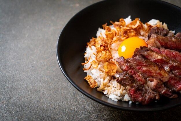 carne en rodajas en un tazón de arroz cubierto con huevo