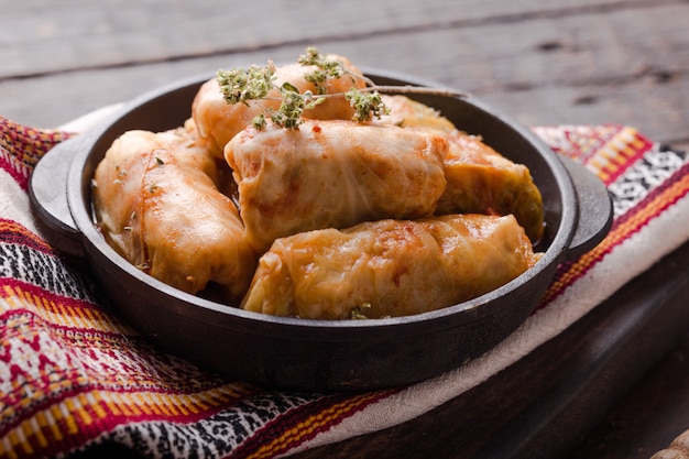 Carne en rollos de col en una sartén negra con salsa