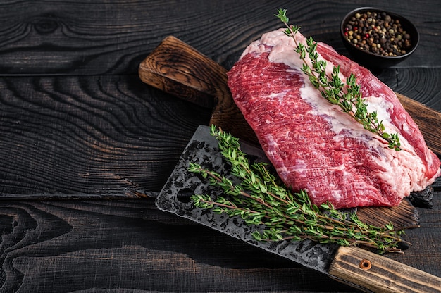 Carne de rosbif redonda cruda fresca cortada en una tabla de cortar de carnicero con cuchilla. Madera negra