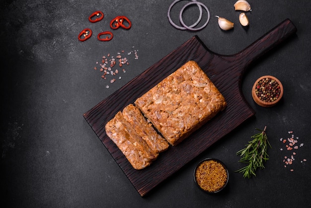 Carne sabrosa o rollo en una tabla de cortar de madera con especias y hierbas