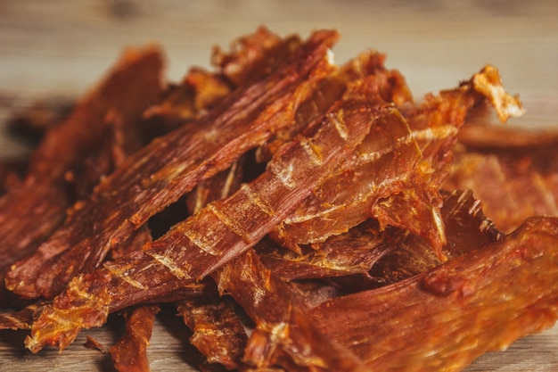 Carne seca deliciosa em um fundo de madeira. produtos em embalagens artesanais. lanche para álcool. foto macro. fechar-se.