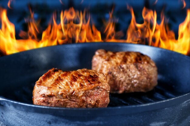 Carne suculenta frita em uma grelha em chamas