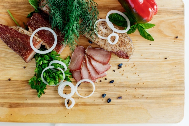 Carne en una tabla de madera con verduras