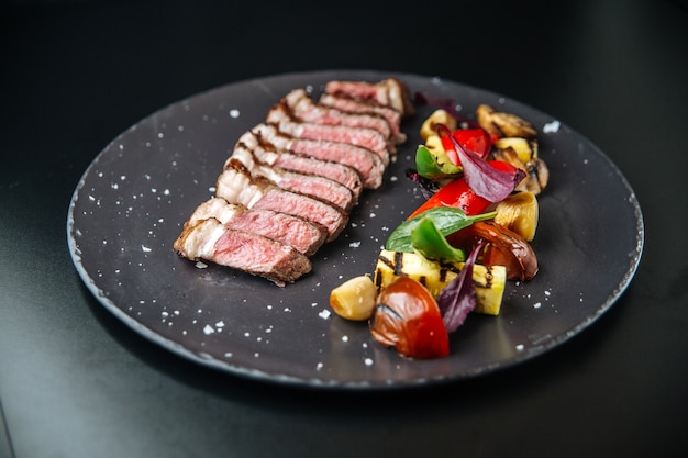 Carne tagliata de bovino com vegetais grelhados na chapa preta