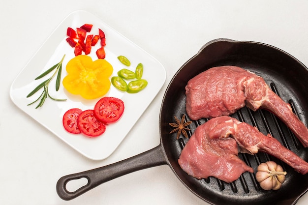 Foto carne de ternera con ajo de hueso y anís estrellado en sartén tomates en rodajas y pimientos en plato blanco