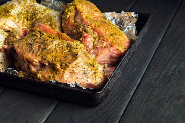 La carne de ternera cruda y las piernas de pollo en una bandeja para hornear se preparan para hornear en el horno. El plato de carne nacional se prepara en vísperas de las fiestas. Espacio publicitario gratuito