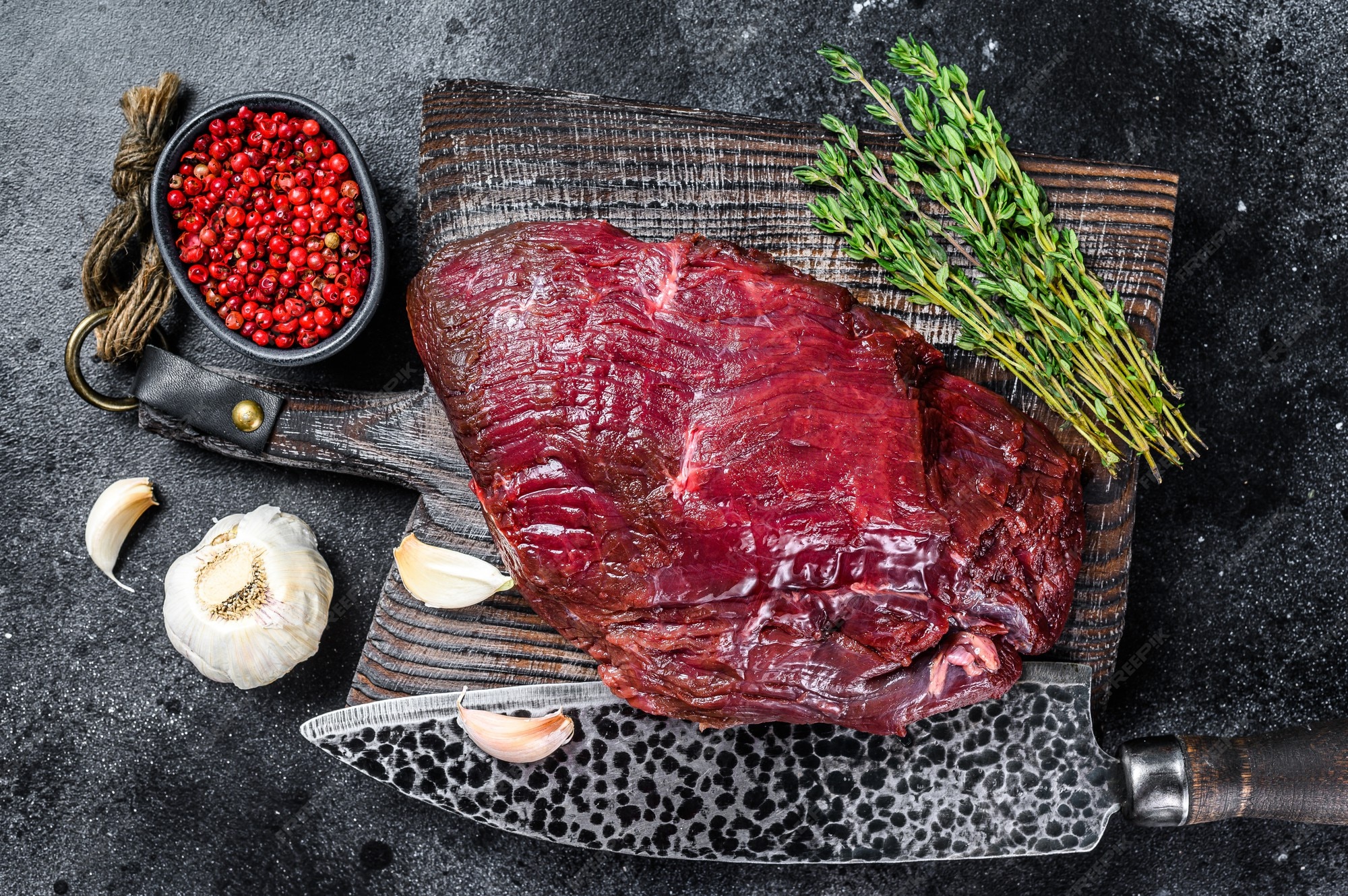 Carne de venado cruda de venado en una tabla de corte con hierbas