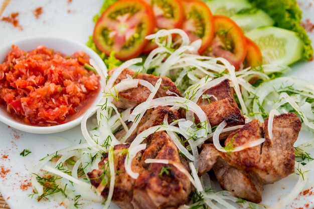 Carne con verduras en un plato blanco.