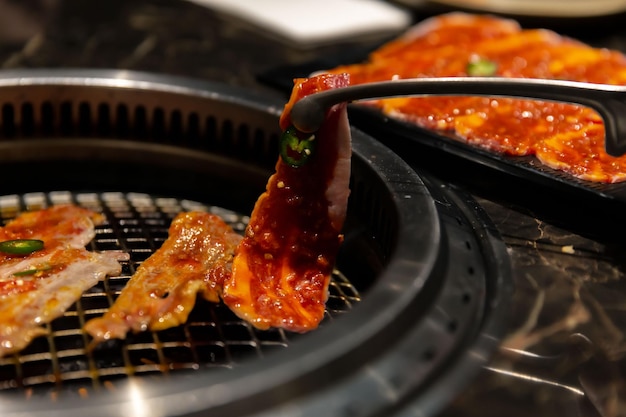 Carne Wagyu marinada chisporroteando en el plato a la parrilla en un restaurante de barbacoa coreano enfoque selectivo