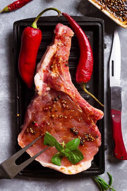 Foto carnes crudas y sartenes con condimentos, aderezos e ingredientes