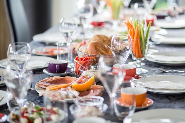 Carnes frías y frutas con verduras en medio de platos en la mesa