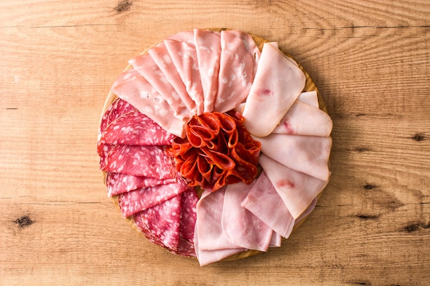 Foto carnes frias na tábua na mesa de madeira presunto, salame, mortadela e salsicha