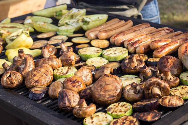 Carnes grelhadas deliciosas assorted com os vegetais sobre o assado no carvão vegetal.