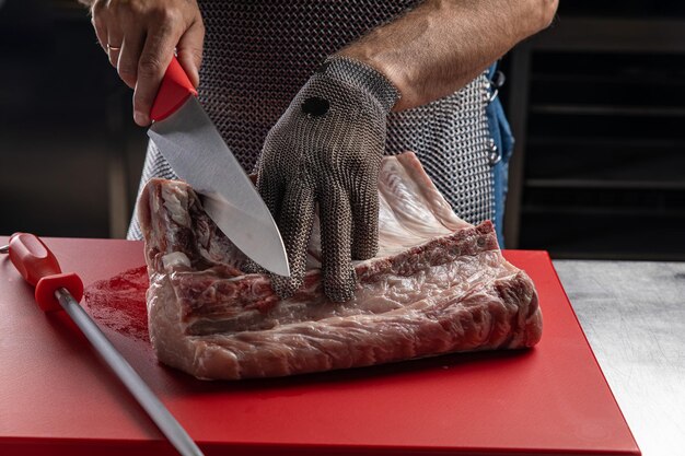 Foto un carnicero corta carne en la cocina.