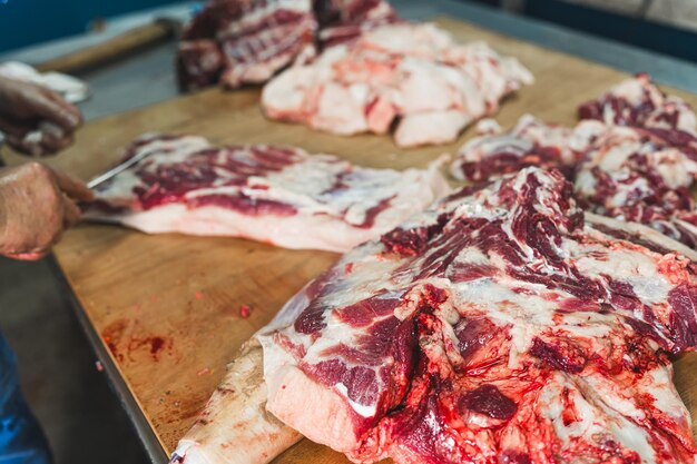 El carnicero corta la carne cruda de un cerdo con un cuchillo en el matadero cortando carne de cerdo