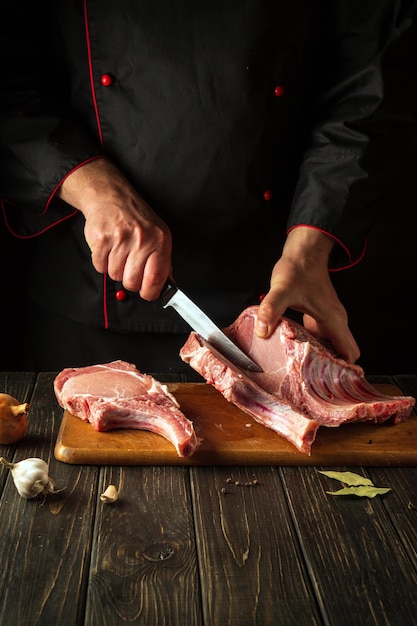 Un carnicero corta costillas crudas en una tabla para cortar antes de preparar un plato de carne Cocina europea