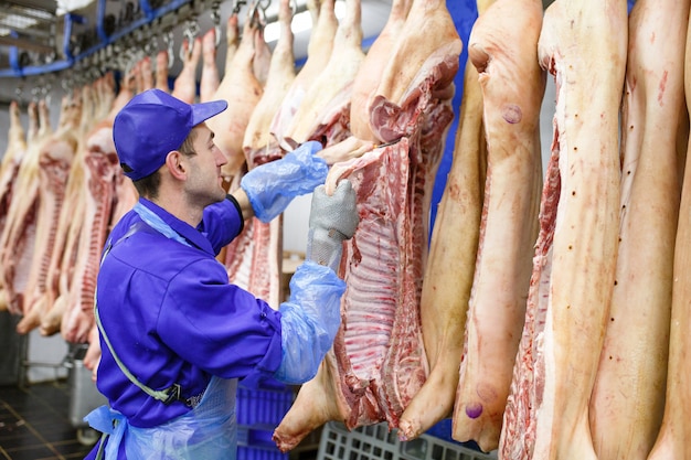 Carnicero cortando carne de cerdo en la fabricación de carne.