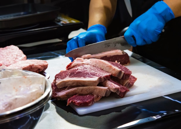 Carnicero cortando carne cruda con cuchillo en la cocina