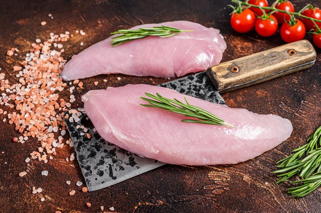 Carnicero Filetes de pavo crudo Filete de pechuga en un cuchillo de carnicero Fondo oscuro Vista superior