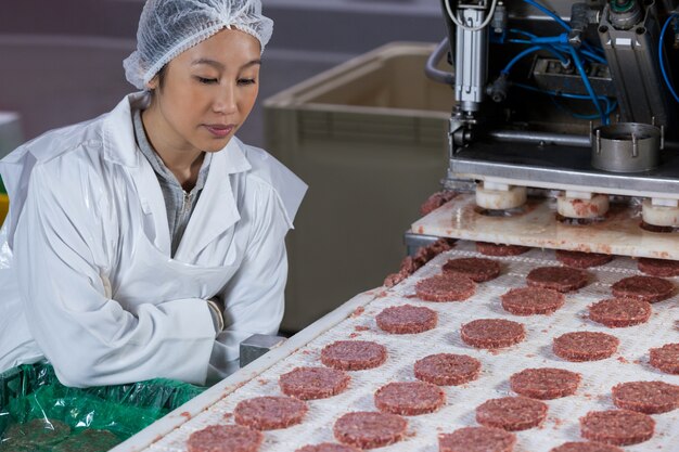 Carnicero hembra procesando hamburguesa