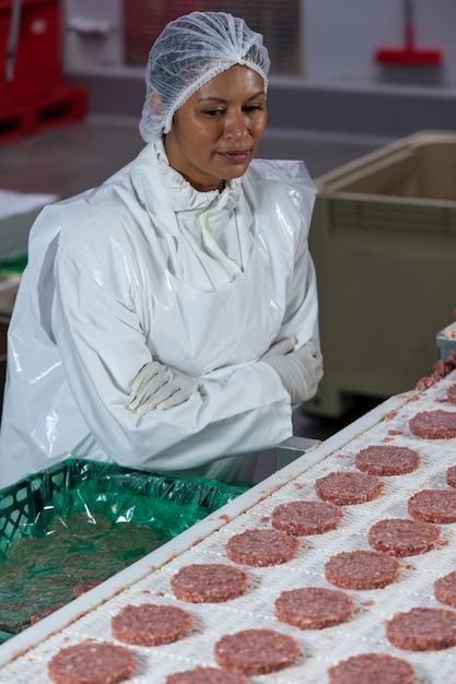 Carnicero hembra procesando hamburguesa