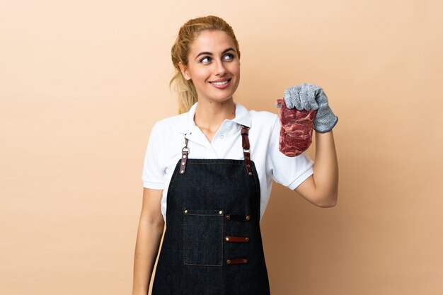 Carnicero mujer vistiendo un delantal y sirviendo carne recién cortada riendo