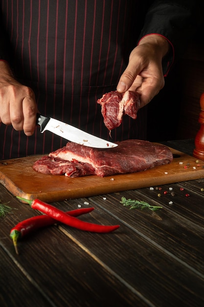 Carnicero o chef corta carne de res fresca cruda en una tabla de cortar antes de hornear o asar