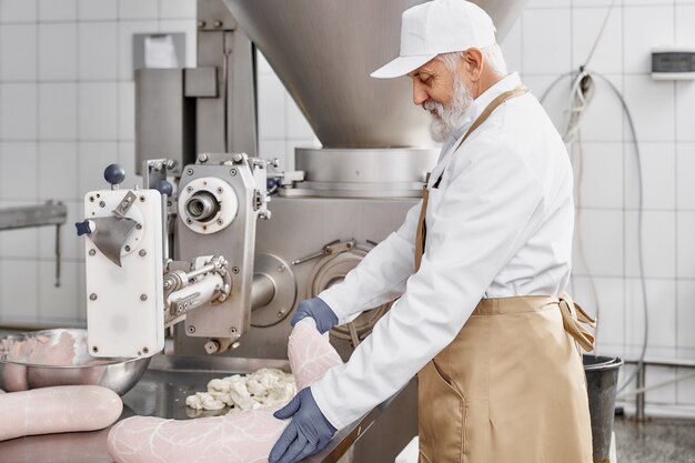 Carnicero trabajando con la producción de salchichas en la fábrica.