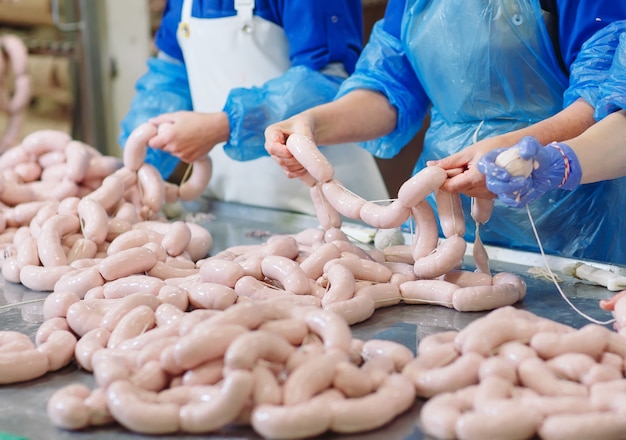 Carniceros procesando salchichas en la fábrica de carne.