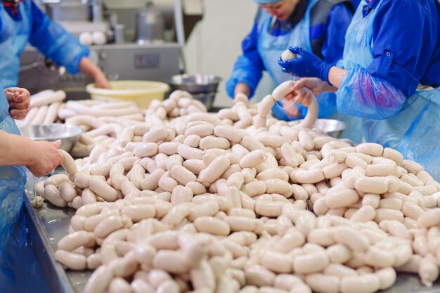 Carniceros procesando salchichas en la fábrica de carne.