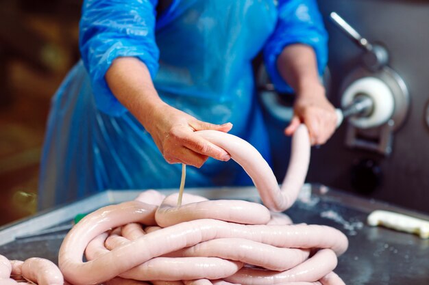 Foto carniceros procesando salchichas en la fábrica de carne.