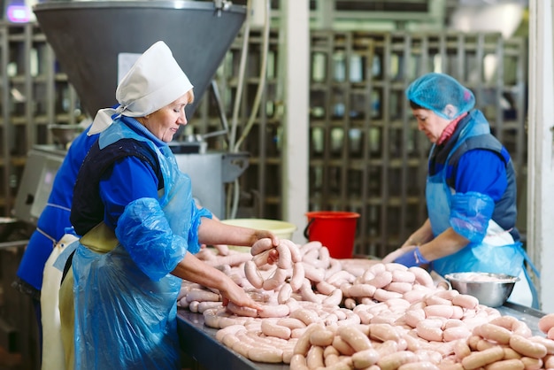 Foto carniceros procesando salchichas en la fábrica de carne.