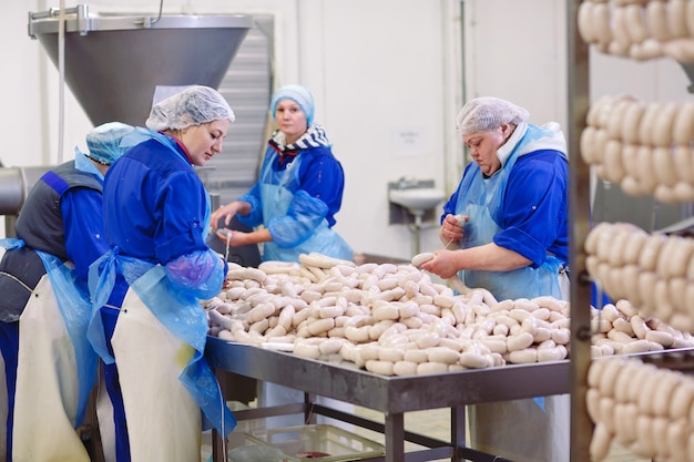 Carniceros procesando salchichas en la fábrica de carne.