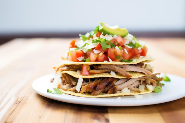 Carnitas altas apiladas en una pila de tortillas de maíz blanco fresco