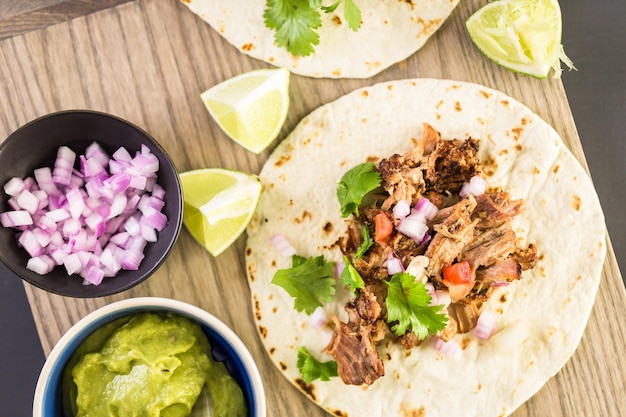 Carnitas de cerdo desmenuzadas con pico de gallo sobre tortilla de harina.