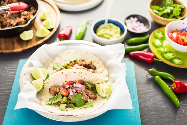 Carnitas de cerdo desmenuzadas con pico de gallo sobre tortilla de harina.