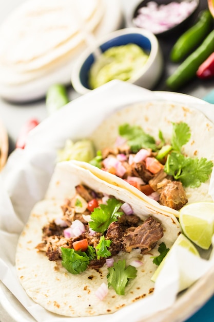 Carnitas de porco desfiado com pico de gallo numa tortilha de farinha.