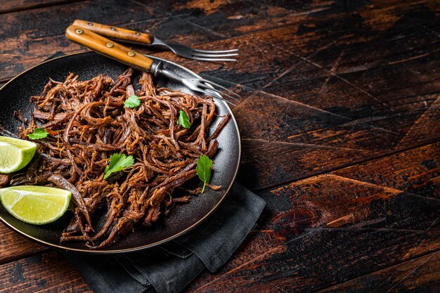 Carnitas em um prato com fatias de aipo e limão Fundo de madeira Vista de cima Copie o espaço