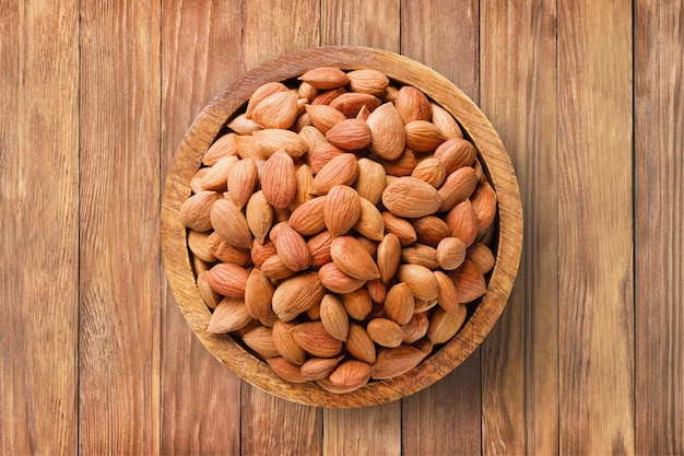 Caroço de damasco descascado em tigela sobre fundo de mesa de madeira, vista superior, comida vegetariana orgânica